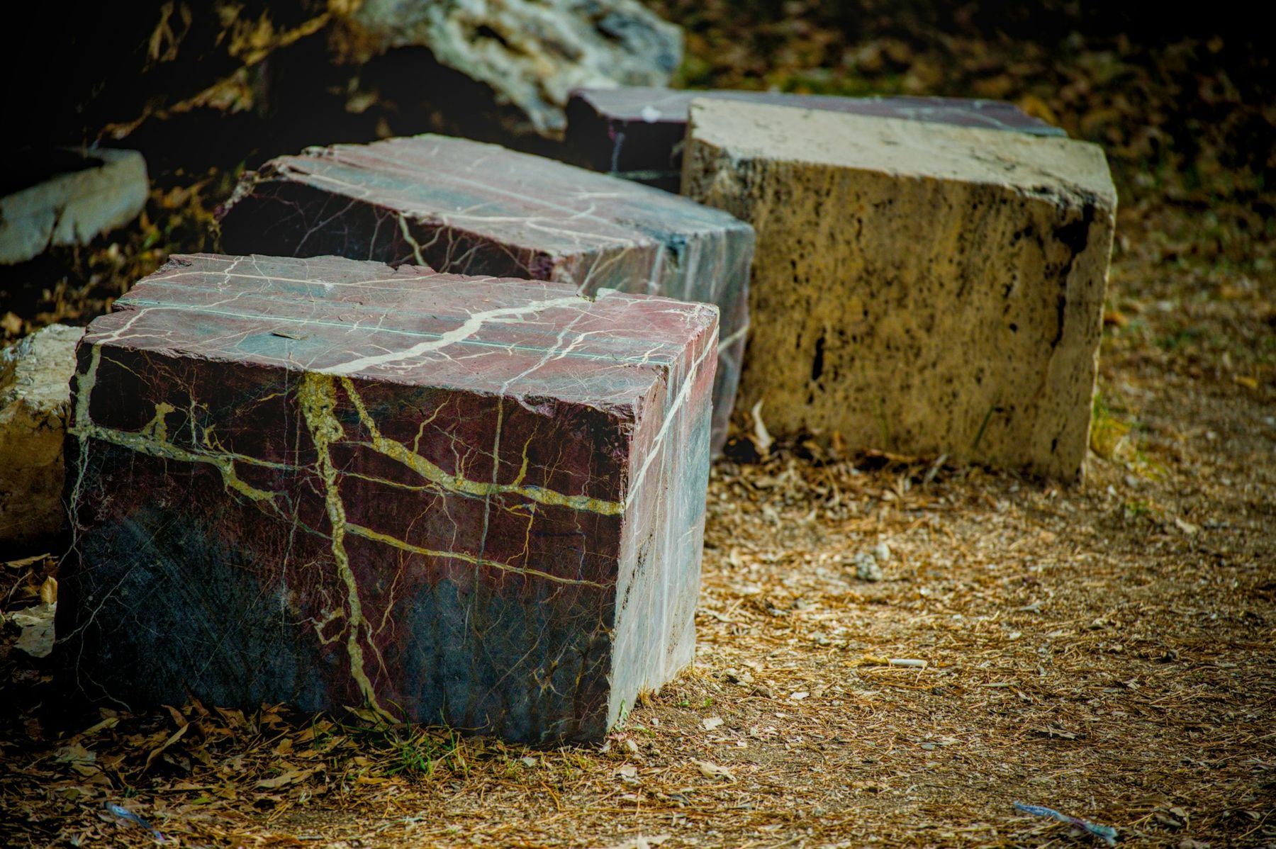 Sawn marble blocks beside a rough travertine block